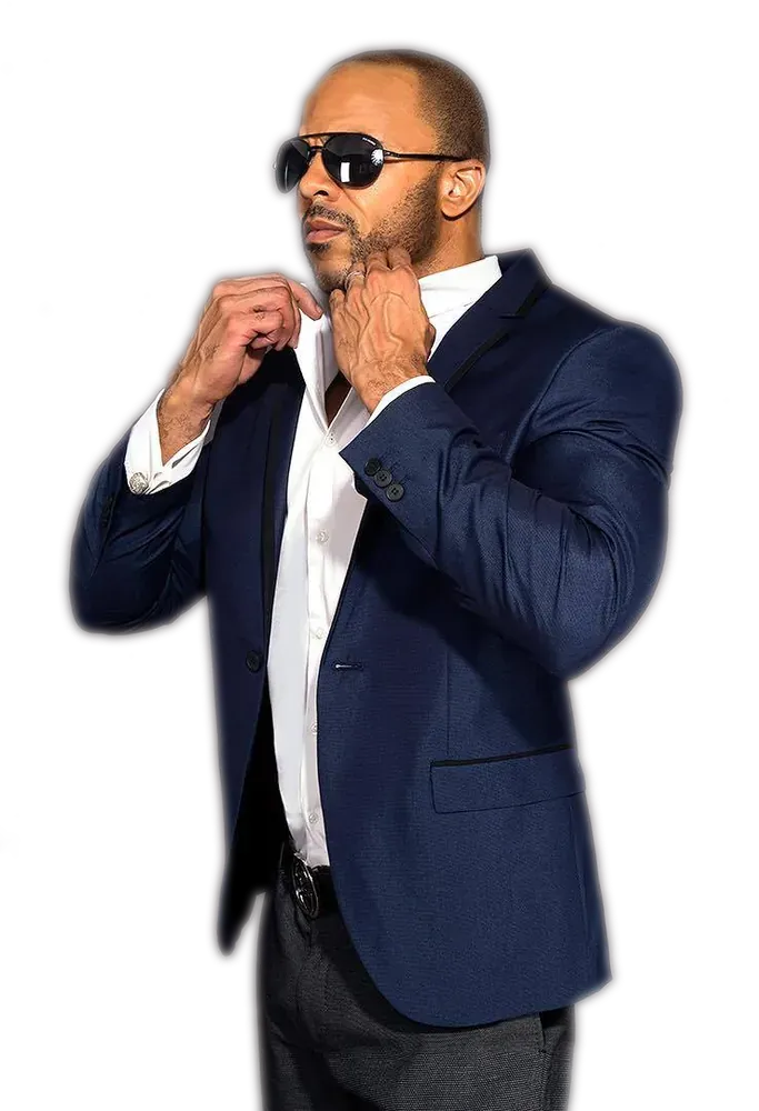 Donavan Wheatfall in a navy suit and sunglasses, adjusting his collar
